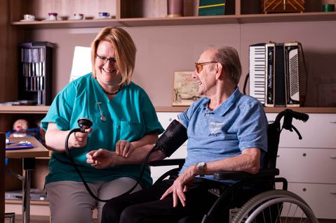 Pflegekraft misst bei einem Bewohner den Blutdruck