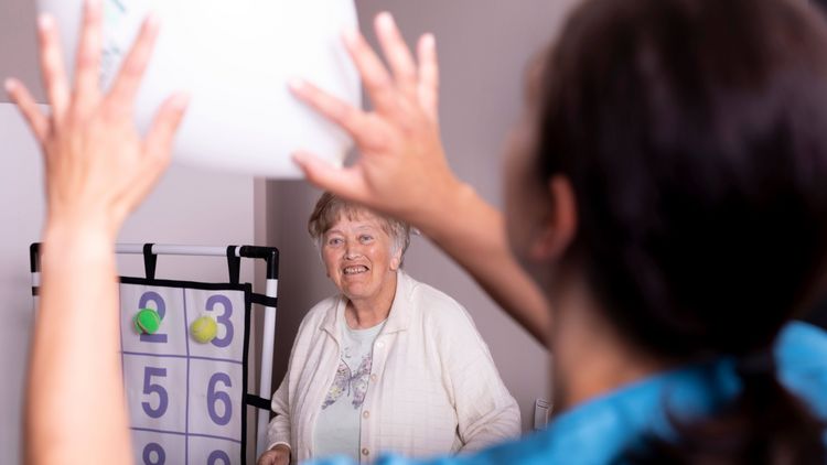 Pflegekraft und Senioren spielen gemeinsam mit einem Ball