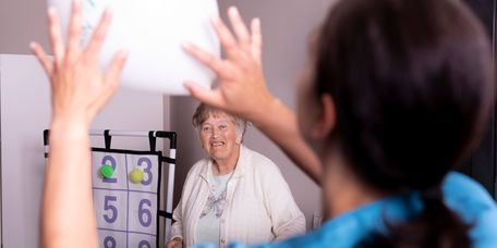 Pflegekraft und Senioren spielen gemeinsam mit einem Ball
