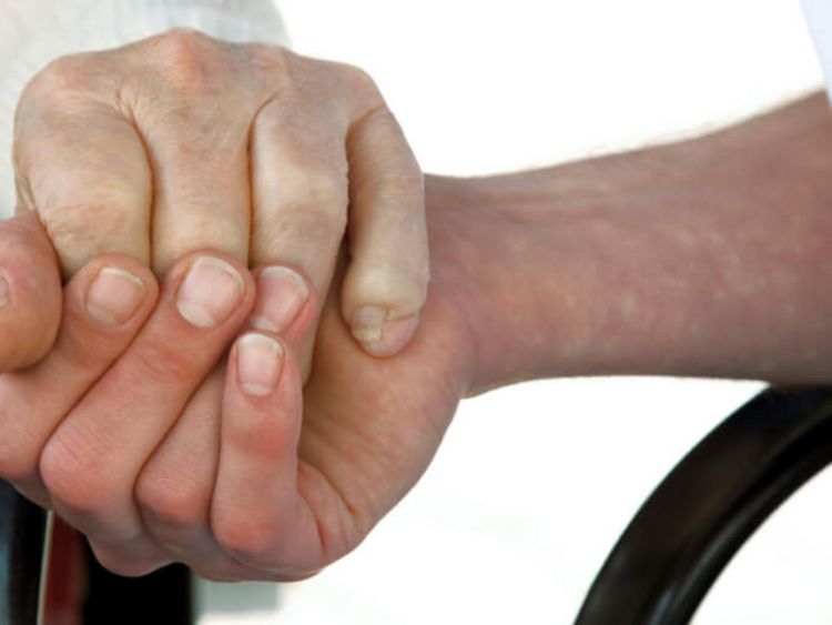 Pflegerin hält Hand eines älteren Bewohners