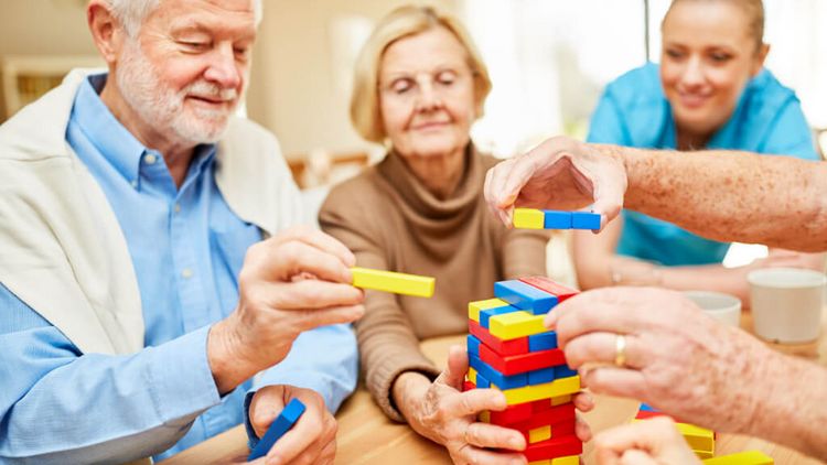 Seniorinnen und Pflegekraft spielen Jenga