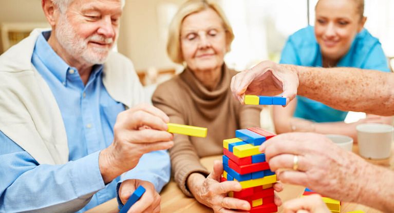 Seniorinnen und Pflegekraft spielen Jenga